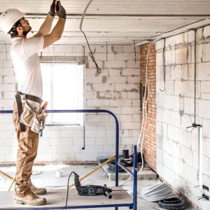 electrician-installer-with-tool-his-hands-working-with-cable-construction-site-min
